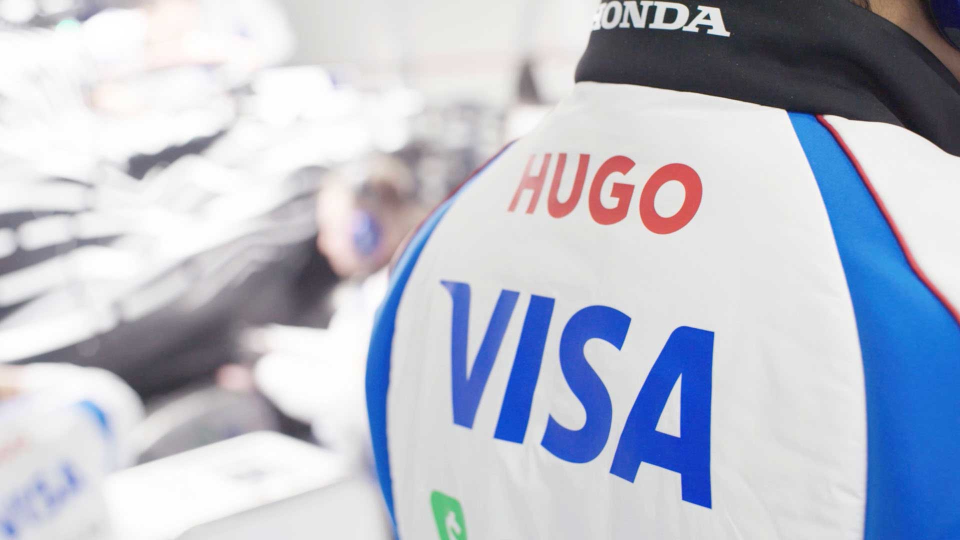 Zoomed in view of “HUGO” and “VISA” logos on the back of a driver jacket. 