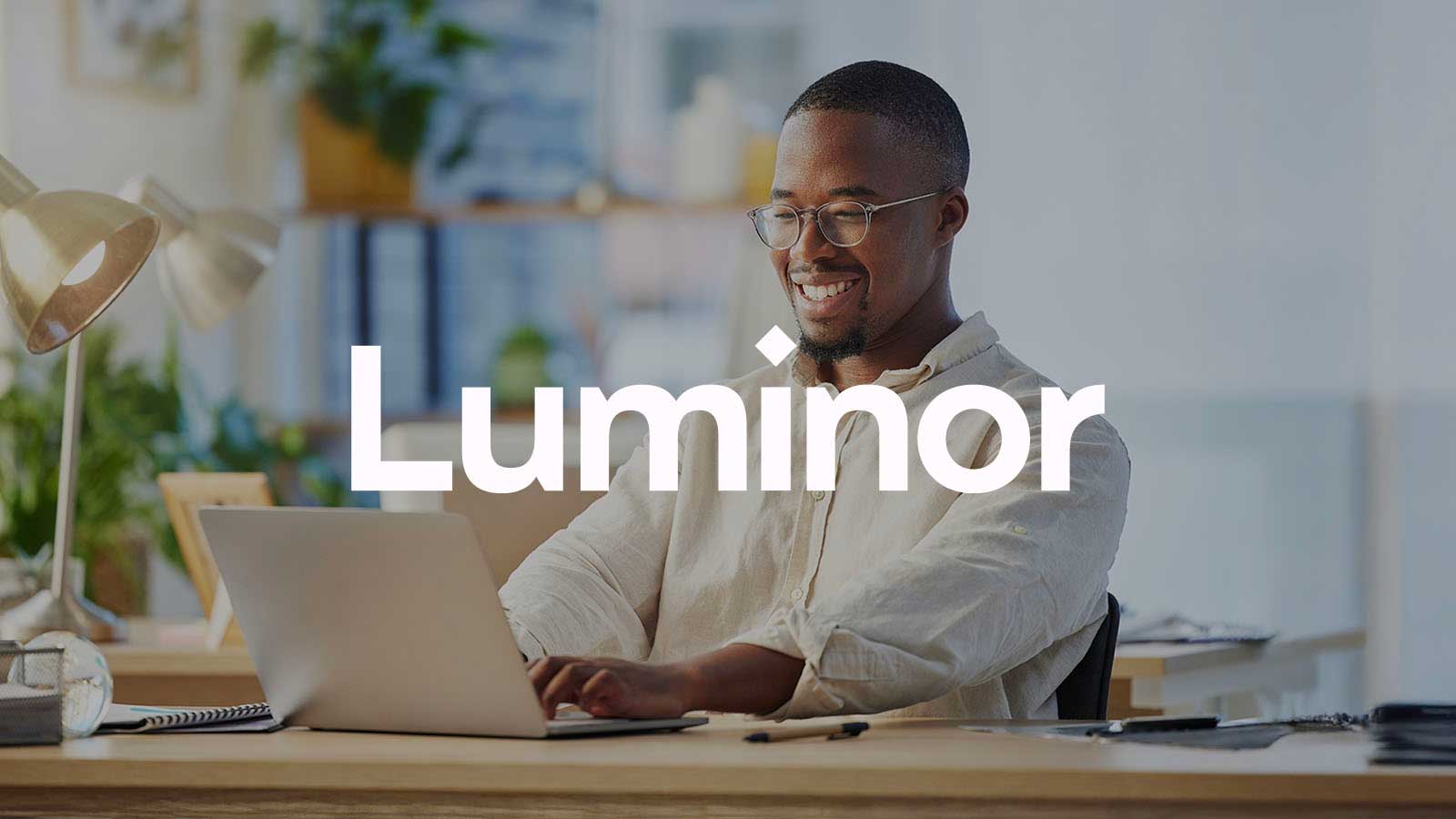Luminor logo overlayed onto a decorative image of a man typing on laptop