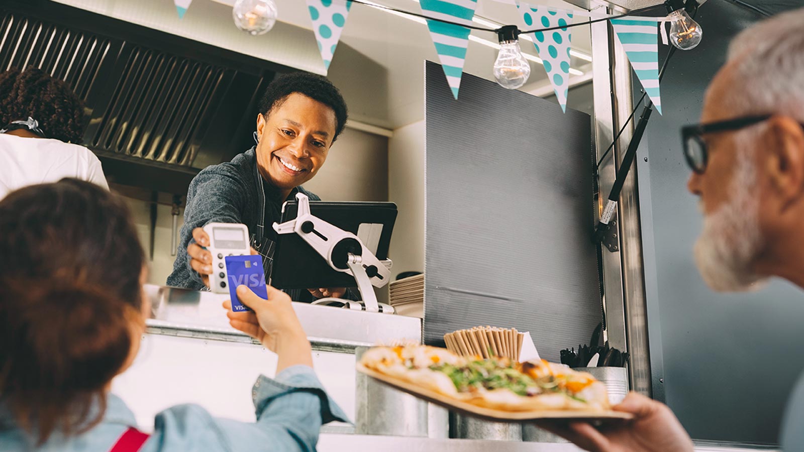 Woman purchasing food at a food truck by tapping her card at the point-of-sale system.