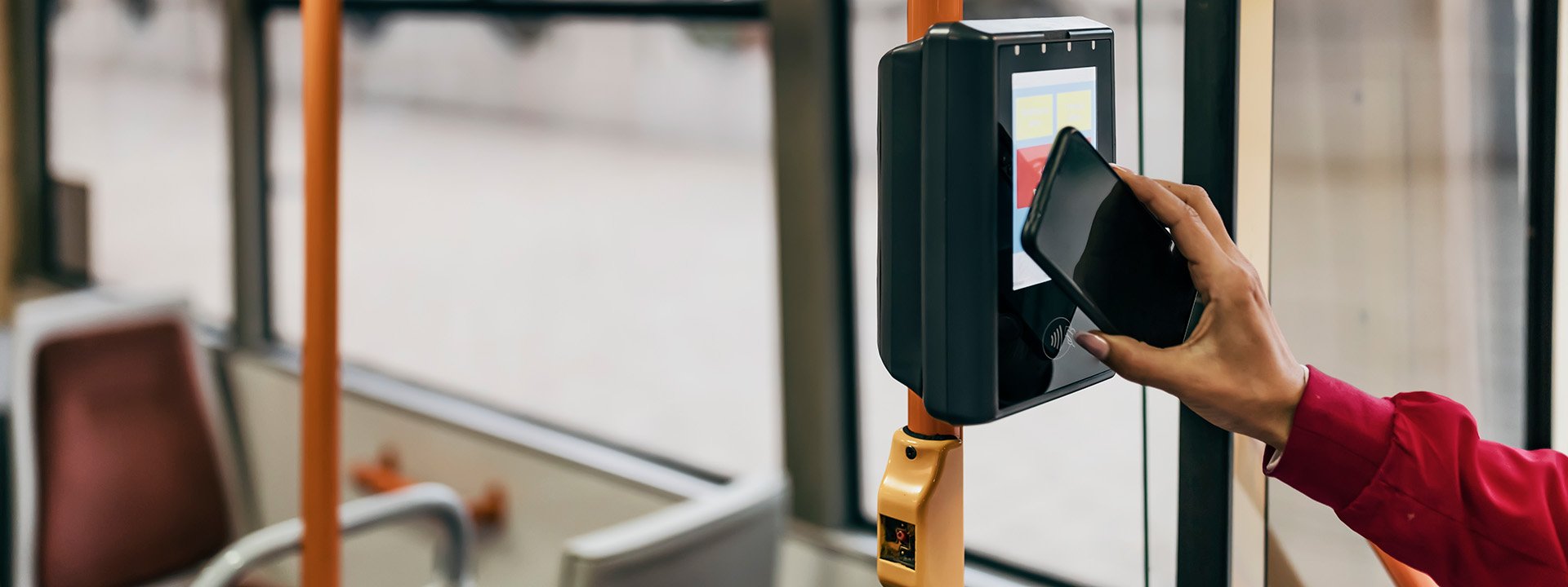 Person holding phone up to reader that has a tap to pay symbol on it.