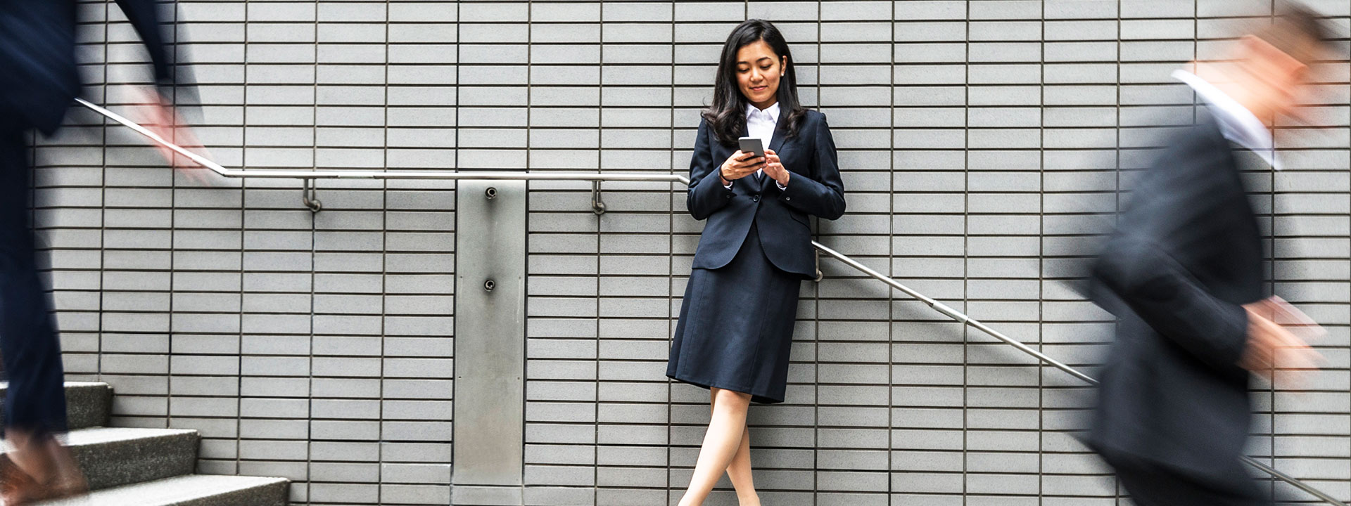 Business woman standing outside looking at her phone