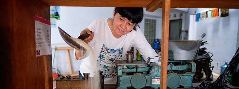 woman reaching over bulk rice bin with scoop