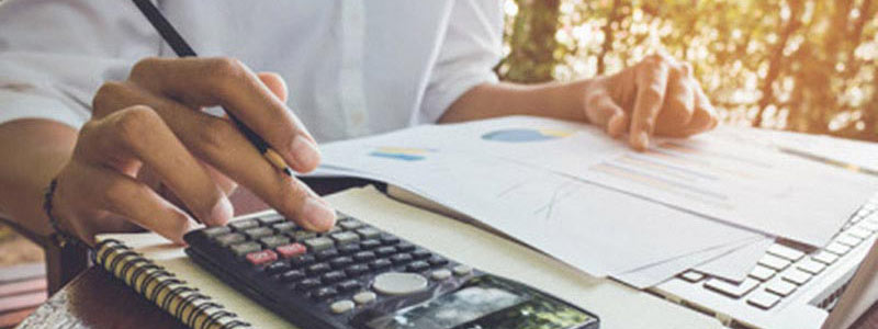 Person sitting at a desk with papers and a calculator.