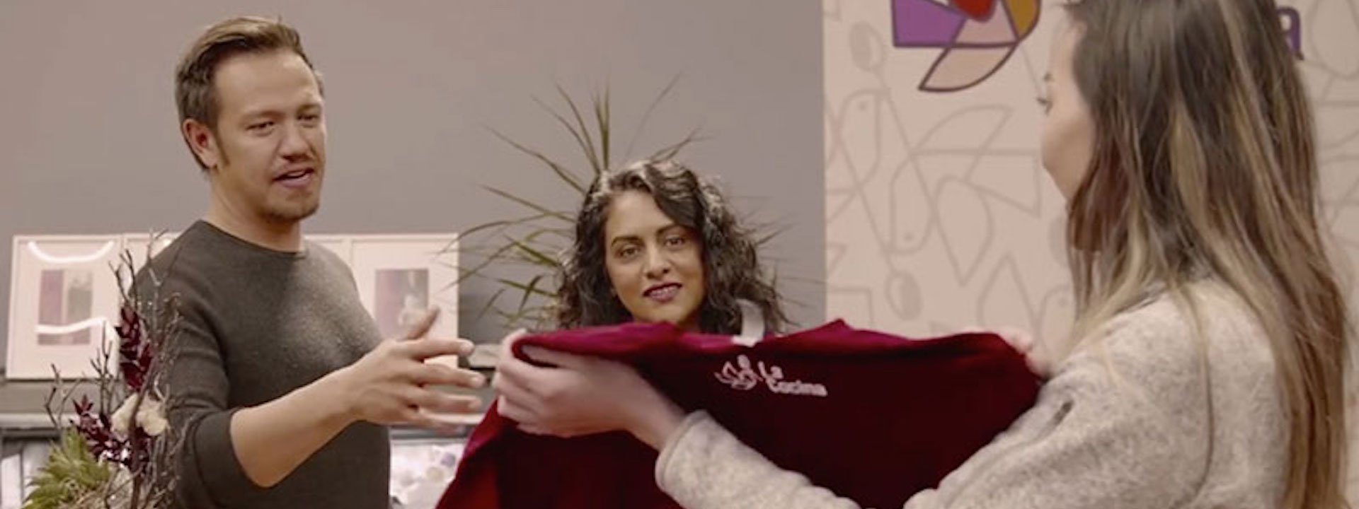 Man and woman shopping for a shirt and talking to a saleswoman in a store.