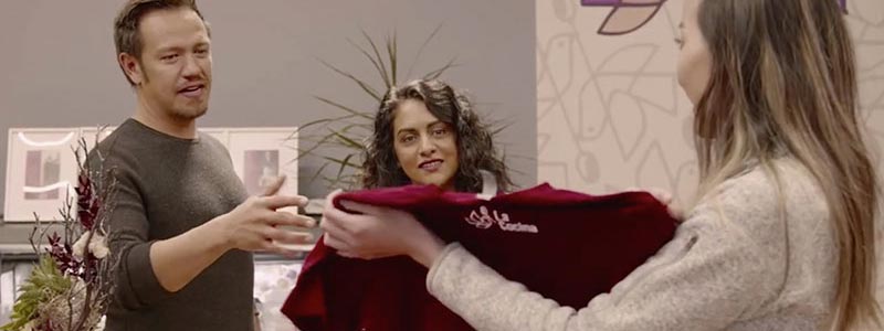 Man and woman shopping for a shirt and talking to a saleswoman in a store.