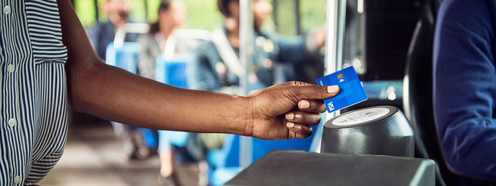 Person holding a Visa contactless card to a terminal on a public bus.