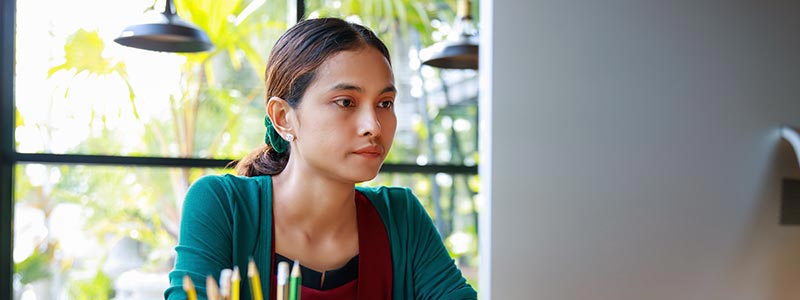 Woman sitting at desk looking at computer screen.