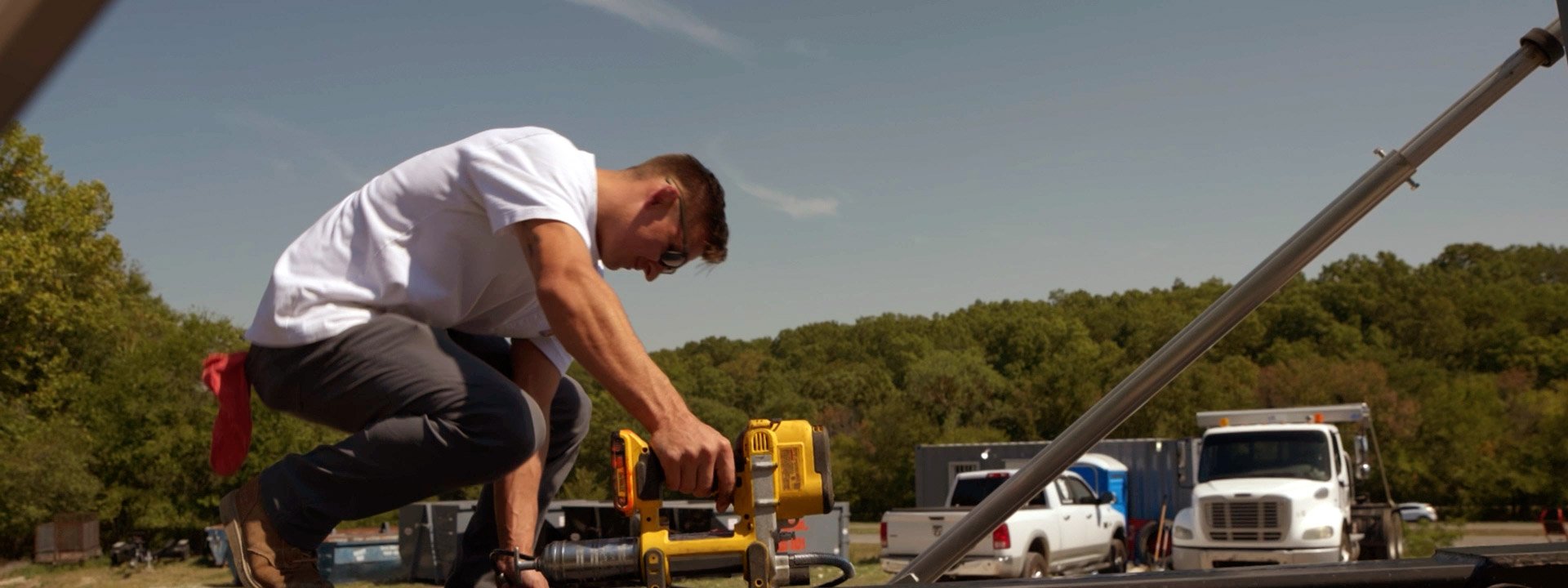 Small business owner in Oklahoma using a power tool on a truck