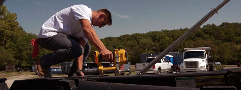 Small business owner in Oklahoma using a power tool on a truck