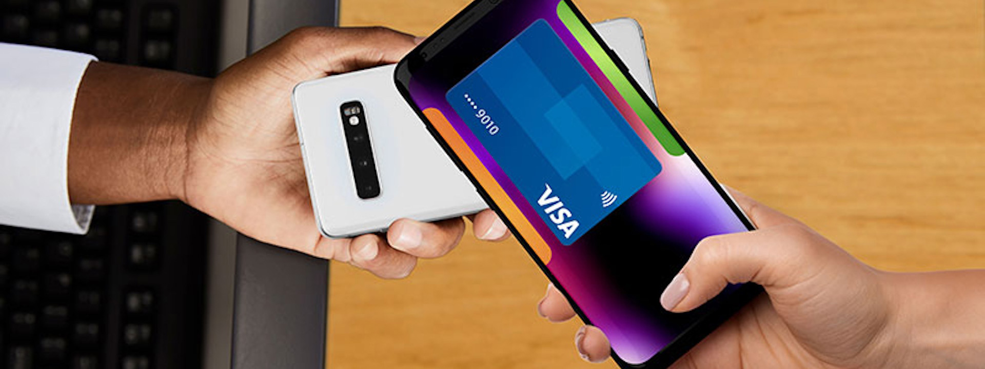 Overhead view of a hand holding a phone with a picture of a Visa card over another phone.