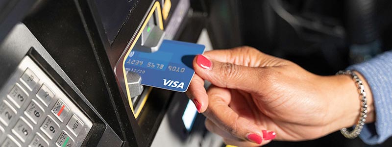 Woman's hand dipping a Visa chip-enabled card at a fuel pump