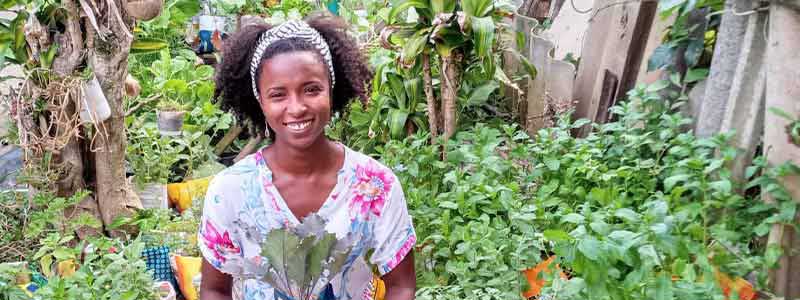 Leirilane Mendes stands among her plants in her medicinal garden