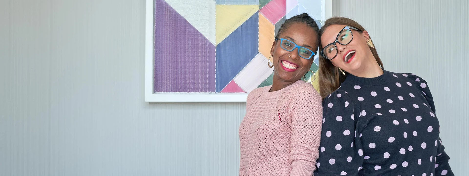 Portrait of two scoops business owners standing back-to-back and smiling at the camera.