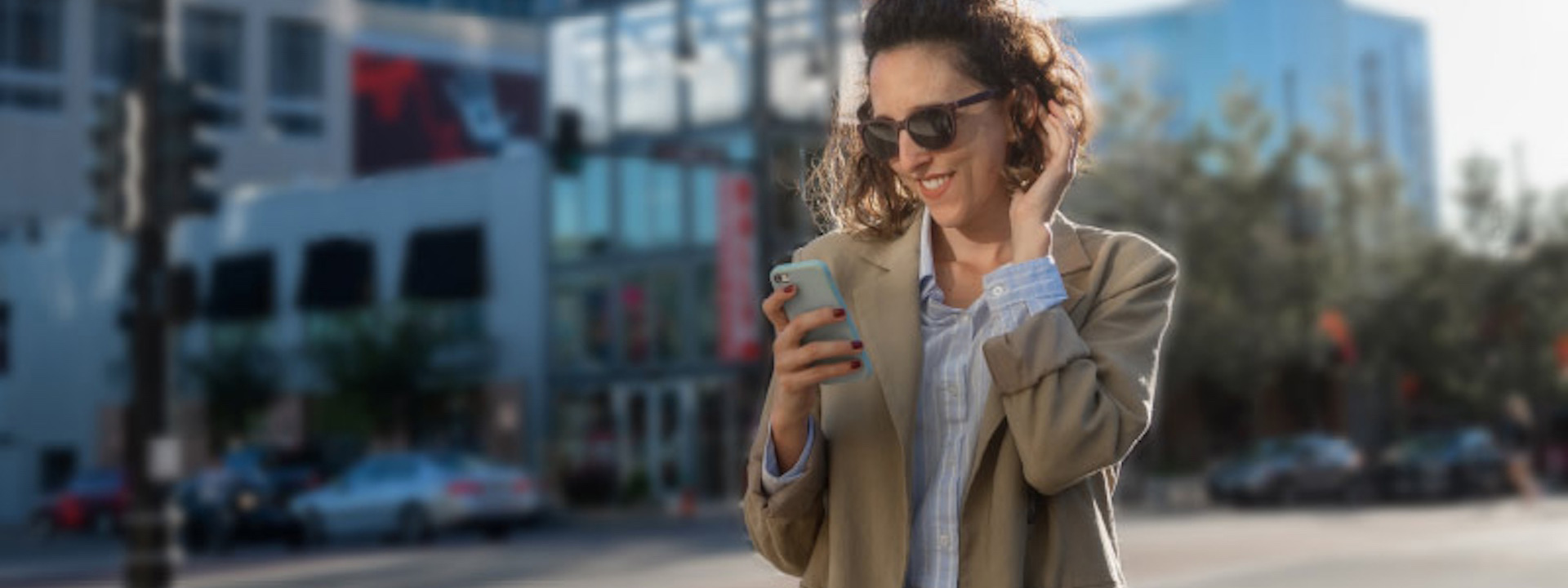 woman wearing sunglasses, looking at her mobile phone