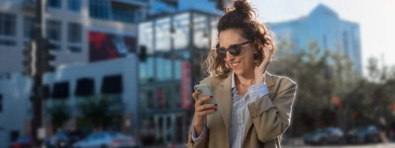 woman wearing sunglasses, looking at her mobile phone