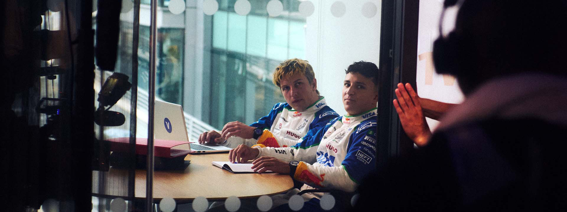 VCARB drivers sit at a desk in a small conference building in front of a video production team.