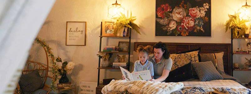 Mother reading to a book to her daughter in bed.