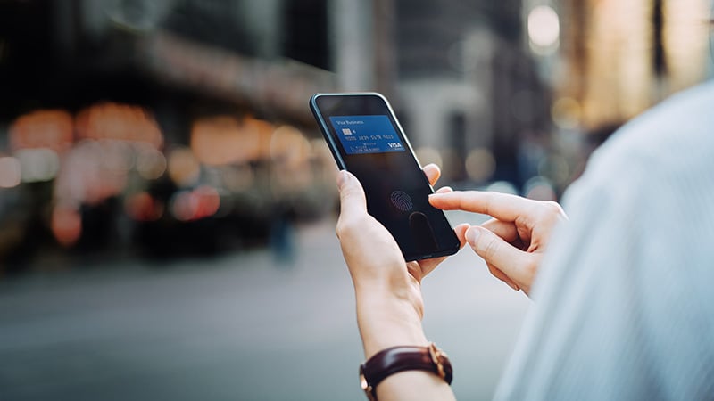 Person using phone that shows the image of a Visa-branded card.