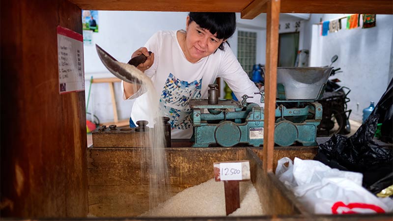 woman reaching over bulk rice bin with scoop