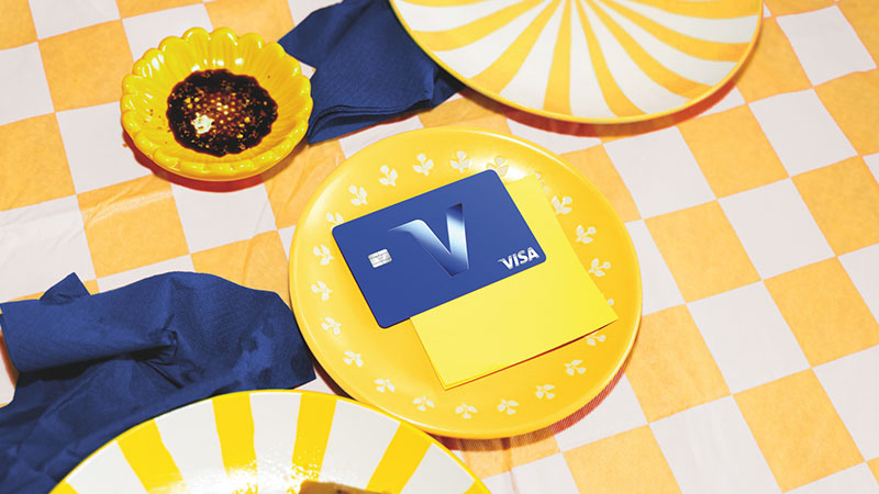 A blue card with Visa’s new branding on a yellow tableset.