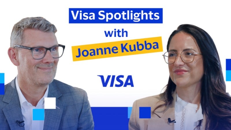 A man and woman engaged in conversation, both smiling, with the text "Visa Spotlights with Joanne Kubba." The Visa logo is centered below.