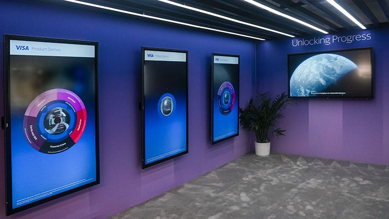 Event room with four screend displaying various graphics representing Unlocking Progress.