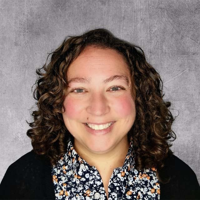 Entrepreneur Kasey Kelly standing against gray background smiling at camera.