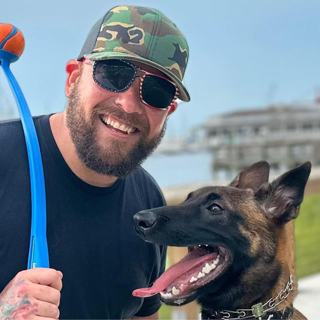 ACP Matt Tarlton smiling at camera next to dog.