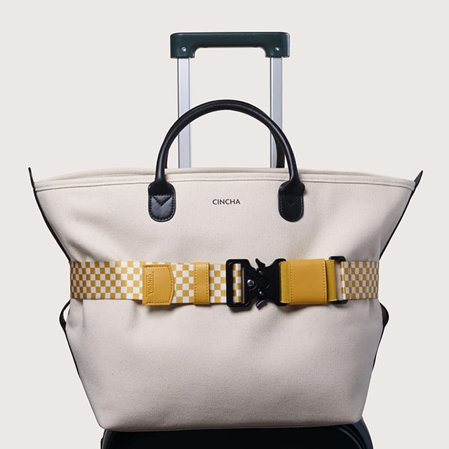 Tote bag perched on a carry-on bag with a Cincha strap.