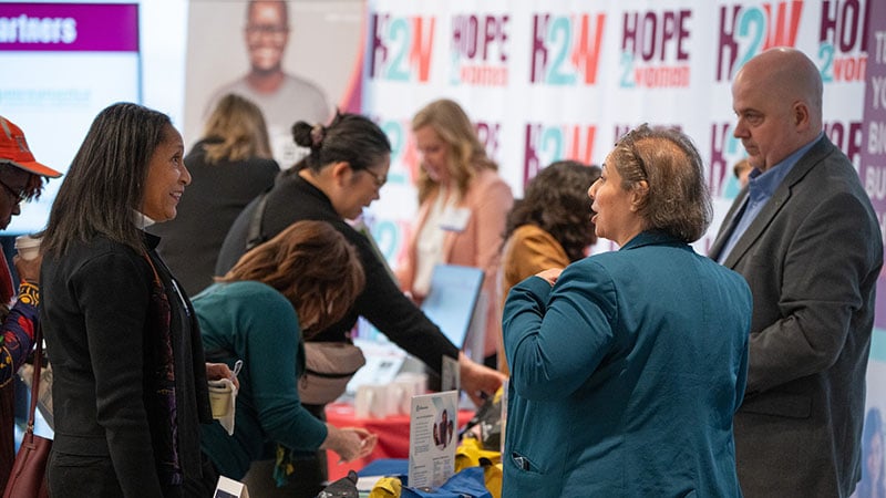 People talking in front of a giveaway table at a financial literacy event