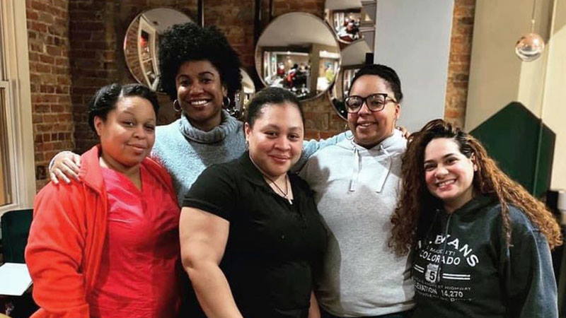 Five woman standing together and smiling.