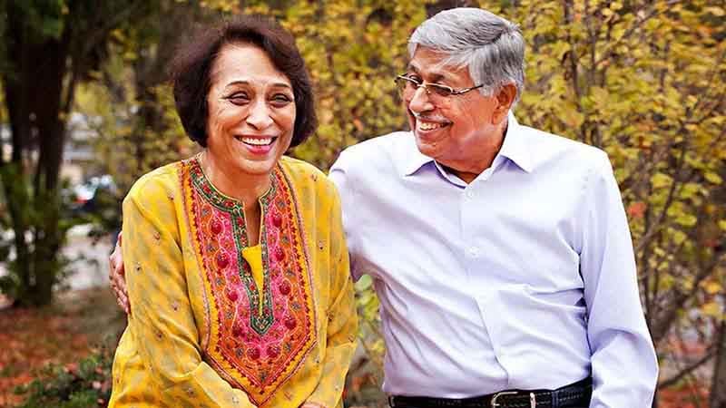 Rajat Taneja’s dad and mom smile at the camera wearing.