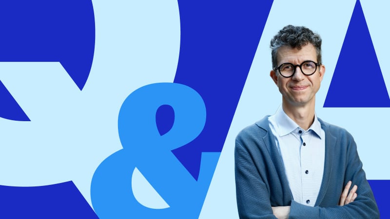 Headshot of Professor Puntoni in front of large, blue letters spelling Q & A