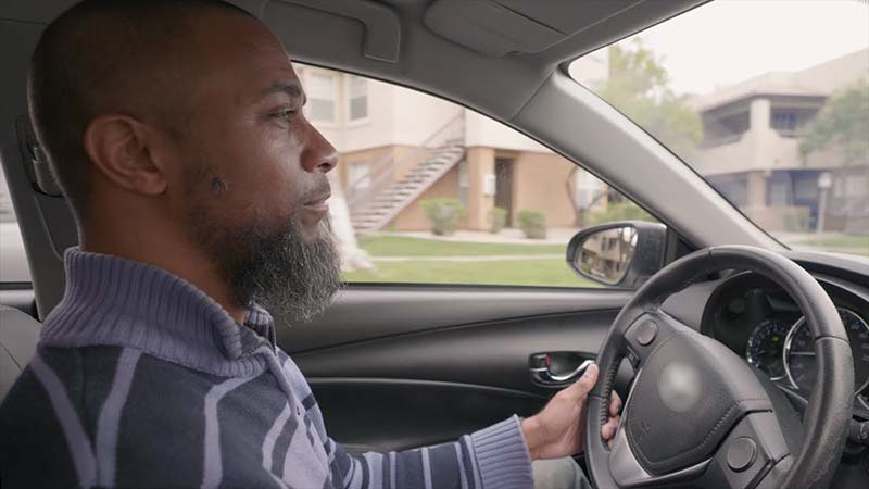 Side view of a man driving a car.